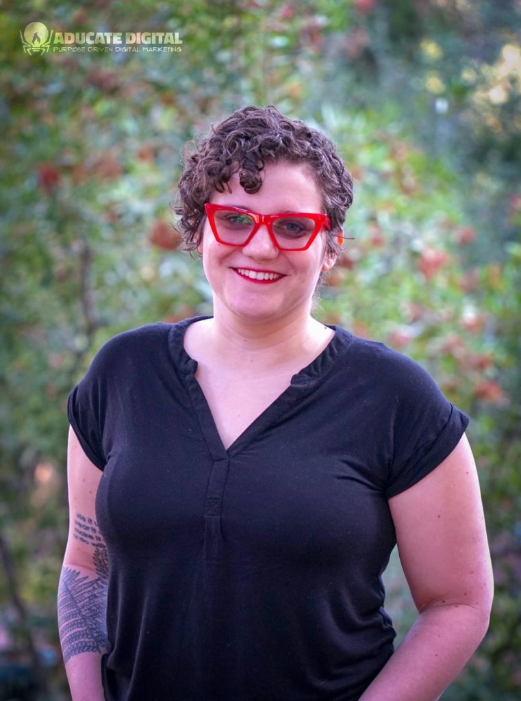 A woman wearing red glasses and a black shirt.