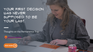 Person sitting at a table smiling while working with art supplies